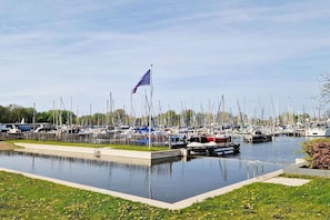A marina with numerous boats docked, a flag, and a small water feature.