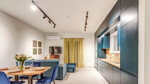 Une cuisine moderne dotée d’un four encastré, un coin repas avec une table dressée pour quatre personnes et un canap é bleu.