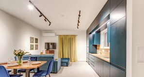 Eine moderne Küche mit Backofen, ein Essbereich mit Tisch für vier Personen und ein blaues Sofa.