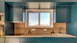 Une cuisine moderne dotée d’une fenêtre, d’appareils électroménagers intégrés et d’un plan de travail en bois.