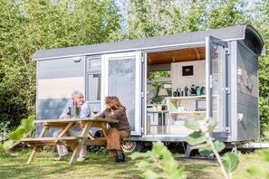 A mobile home with a dining area and a kitchen visible through the open door.