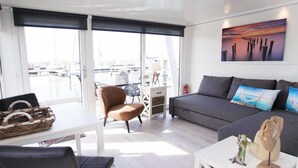 Un salon moderne avec un canapé, une table à manger et une vue sur le port de plaisance.