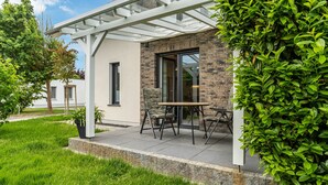Ein modernes Haus mit Terrasse, Tisch und Stühlen.
