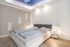 A modern bedroom with a bed, nightstands, decorative wall art, and a skylight ceiling. - Apartment 'Für 2 Personen 35 M²' with Private Terrace, Private Garden and Wi-Fi (Koserow)