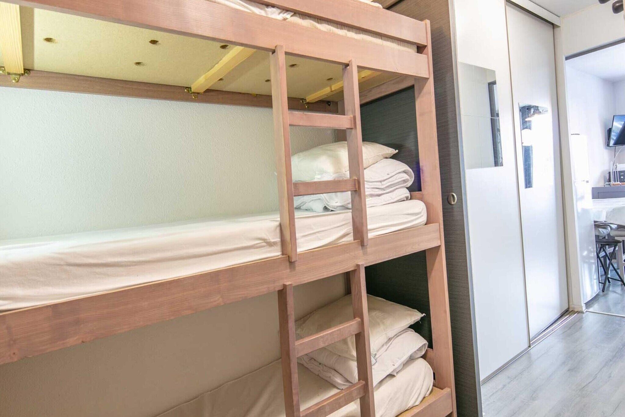 Ein Stockbett mit einer Leiter, ein kleiner Tisch und ein Fernseher in einem modernen Zimmer.