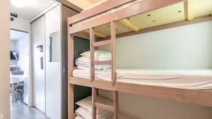 Ein Stockbett mit Holzbettrahmen, ein Schreibtisch und ein Stuhl im angrenzenden Raum.