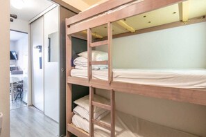 Ein Stockbett mit Holzbettrahmen, ein Schreibtisch und ein Stuhl im angrenzenden Raum.