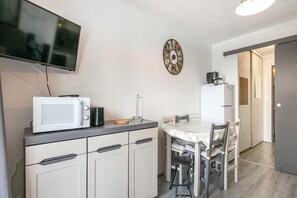 Eine kompakte Küche mit Mikrowelle, Kaffeemaschine und einer Wanduhr.