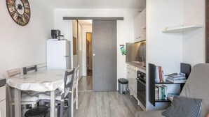 Ein kompakter Wohnbereich mit Essplatz, Küchenzeile und einer Sitzecke mit Büchern.