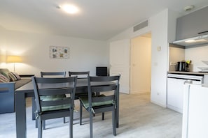 A dining area with a table and chairs, a kitchen with appliances, and a door leading to another room. - Scenic Riviera home near sea (Grasse)