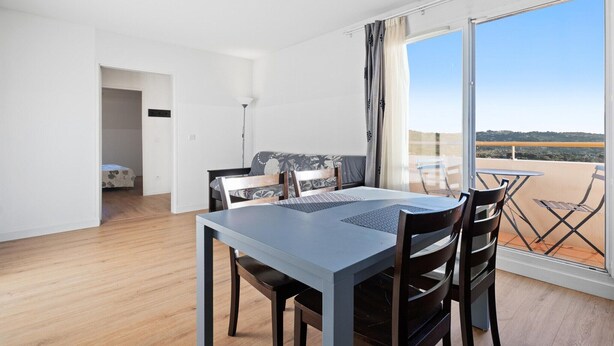 Una habitación con una mesa de comedor, sillas, un sofá y un balcón con vistas.