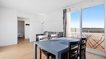 Une pièce comprenant une table à manger, des chaises, un canapé et un balcon avec vue.