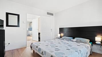 Une chambre à coucher comprenant un lit, des lampes de chevet, une armoire et une porte donnant sur une salle de bain.