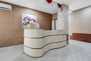 Un mostrador de recepción con diseño curvo, un aire acondicionado de pared y un cartel en la pared.