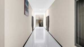 A long, narrow hallway with a polished floor, flanked by plain walls and doors on both sides. - Cozy Twin Escape with Free WiFi and Parking (Padang)