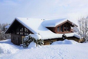 Eine Holzhütte mit geneigtem Dach, umgeben von Schnee.
