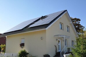 Ein zweistöckiges Haus mit Satteldach, einer Veranda und einem kleinen Garten.