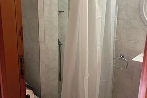 Suihkutilassa on suihkupää, pyyhelenkki ja wc, jotka ovat näkyvissä.