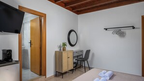 Ein Zimmer mit einem Bett, einem Schreibtisch, einem Stuhl, einem Fernseher, einem Spiegel und einem Handtuchhalter.
