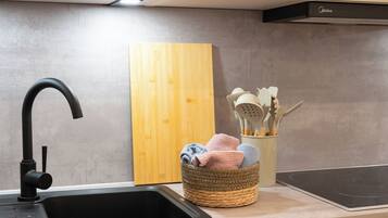 Eine Küche mit modernem Wasserhahn, Schneidebrett aus Holz, einem gewebten Korb mit Küchenutensilien und einem eingebauten Herd.