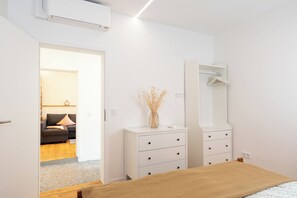Ein Schlafzimmer mit Bett, Kommode, Spiegel und einer Tür zu einem Wohnbereich.