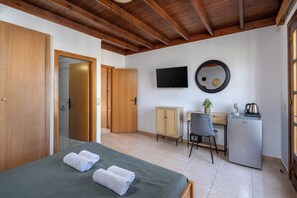 A room with a bed, a desk, a television, and a refrigerator. - Pinotsi Room 3- Double bed (Simi)