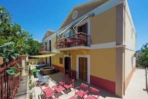 A two-story building with a balcony, outdoor seating, and a hot tub. - Pinotsi Room 3- Double bed (Simi)