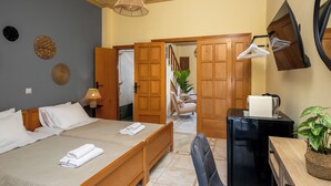 Una habitación de hotel con cama, escritorio, silla, espejo y una planta.