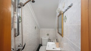Un baño pequeño con ducha, inodoro, lavamanos y espejo.