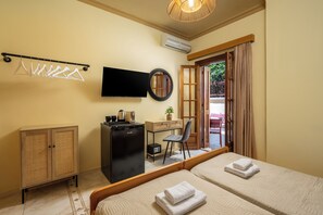 A hotel room with two beds, a desk, a television, a wardrobe, and a view through a door. - Pinotsi Room 5 -2 single (Simi)