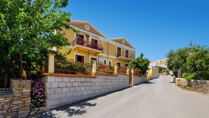 Un edificio de dos pisos con balcones, una pared de piedra y cielo despejado.
