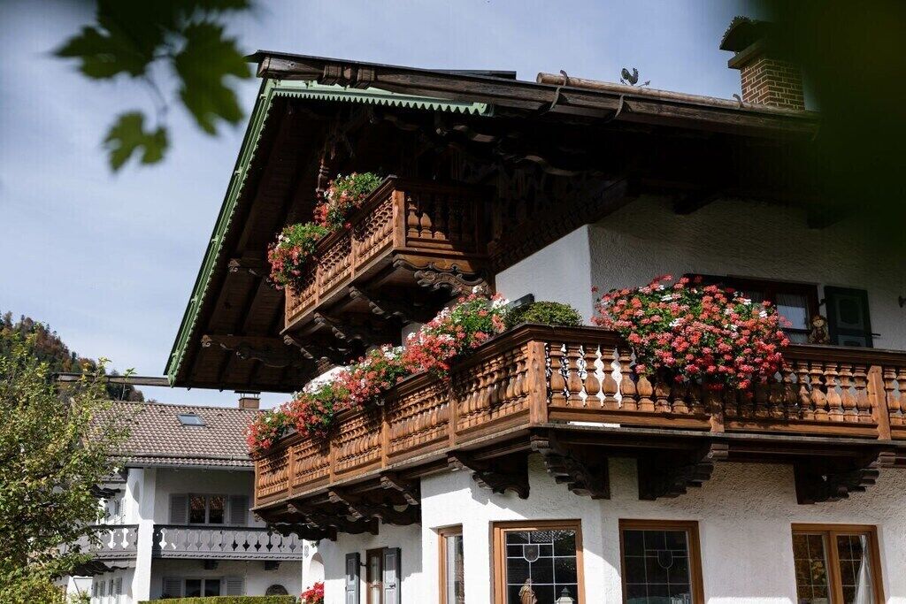 Ein traditionelles Chalet mit Holzbalkonen, weißen Wänden und Blumenkästen.