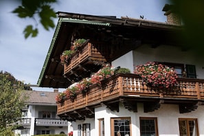 A traditional chalet with wooden balconies, white walls, and flower boxes. - Holiday apartment with 1 bedroom (Wallgau)