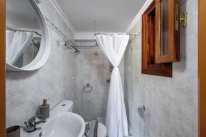 A bathroom with a bathtub, toilet, sink, and a mirror. - Pinotsi Room 2 - 2 single (Simi)