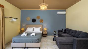 Un dormitorio con cama, lámparas de noche, aire acondicionado instalado en la pared y un sofá gris.