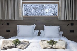 A neatly made bed with white linens and two pillows, a window with curtains, and a view of snow-covered trees. - Holiday apartment Sëléna (Bruson)