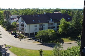 Ein mehrgeschossiges Gebäude mit Flachdach, umgeben von Grünflächen und einer gewundenen Straße.