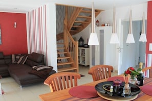 A modern living room with a sofa, wooden dining table, chairs, and a staircase. - Holiday home in Zierow with swimming pool (Zierow)