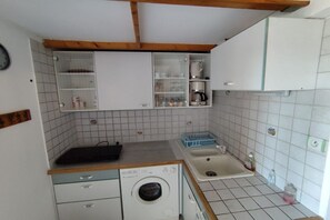 A compact kitchen with a washing machine, sink, and cabinets. - Les Sables D'or N°28 - 2P6 (Agde)