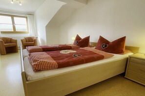 A bedroom with a bed, two chairs, a nightstand, and a window. - Holiday apartment with 2 bedrooms (Nesselwang)