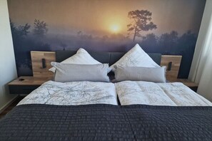 Ein Doppelbett mit gemustertem Bettbezug, zwei Kissen und einem Kopfteil mit Baumkontur.