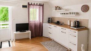 Eine kleine Küche mit Fernseher, Kaffeemaschine und einer Wanduhr.
