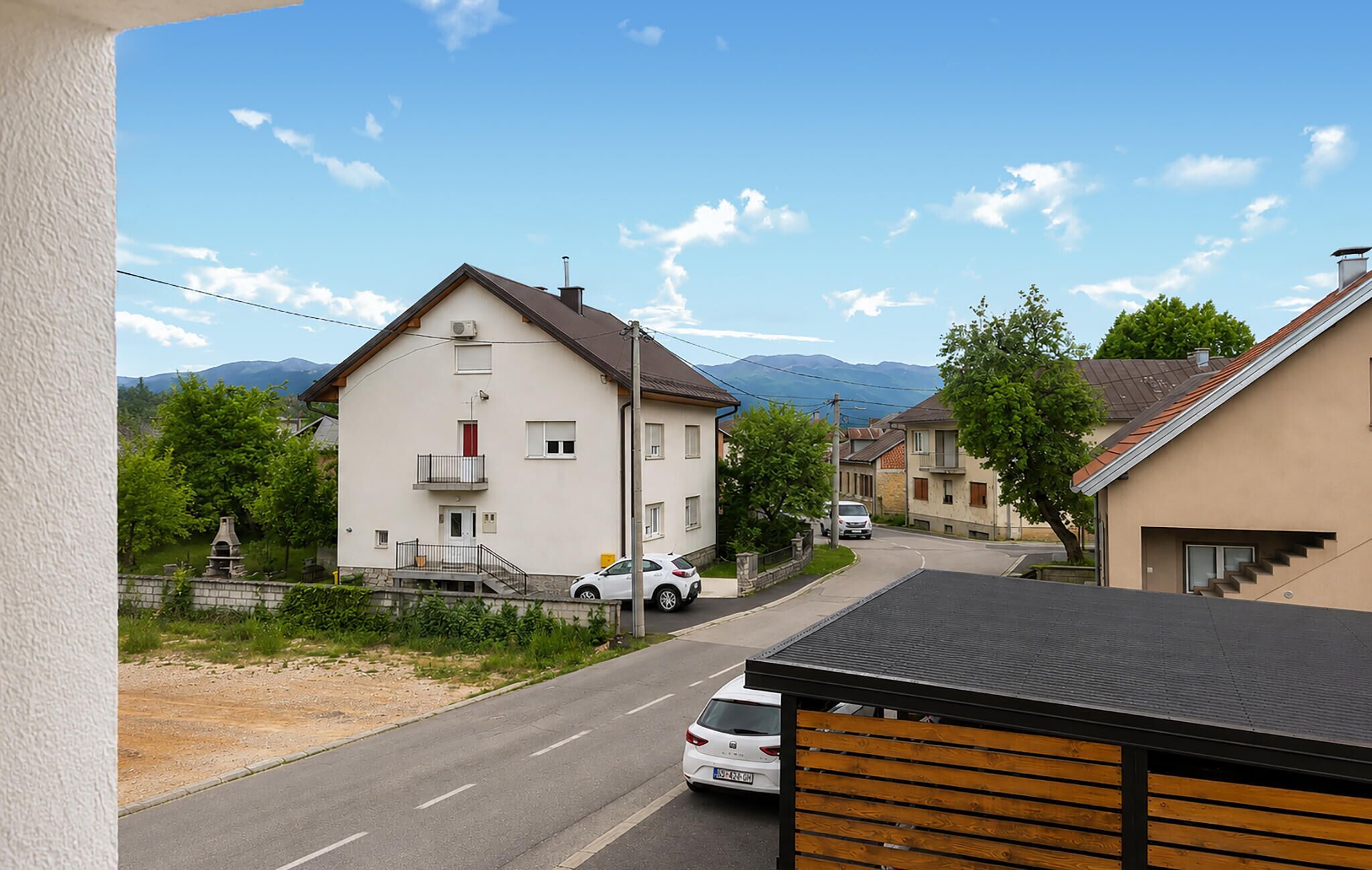 A residential street with houses, a clear sky, and mountains in the background.