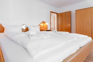 Ein Doppelbett mit weißer Bettwäsche, eine Nachttischlampe und ein Holzschrank.