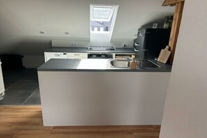 Una cocina compacta con horno integrado, un lavamanos y una ventana sobre la encimera.