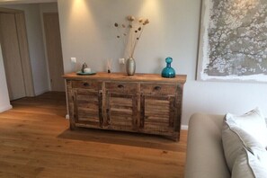 A wooden console table with drawers, a vase with dried flowers, and a blue decorative object. - Holiday apartment in Kirchheim with barbecue (Kirchheim)