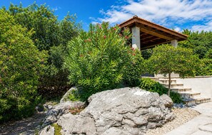 A stone rock in a garden with a wooden pergola structure. - Beautiful home in Korcula (Korcula)