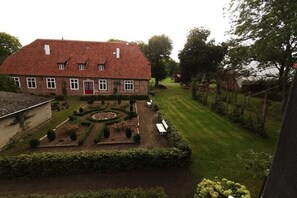 Ein traditionelles Haus mit rotem Ziegeldach, einem Garten mit kreisrunder Rasenfläche und einer roten Tür.