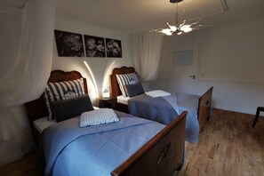 Ein Schlafzimmer mit zwei Betten, einem Nachttisch mit Lampe, einer Deckenleuchte und einem Kunstwerk an der Wand.