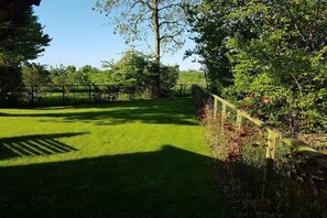 A well-maintained grassy area with a wooden fence, trees, and a clear sky. - Holiday home with 3 bedrooms (Bruinisse)